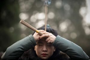 Une femme brûle des bâtons d'encens, photographie Thomas Peter