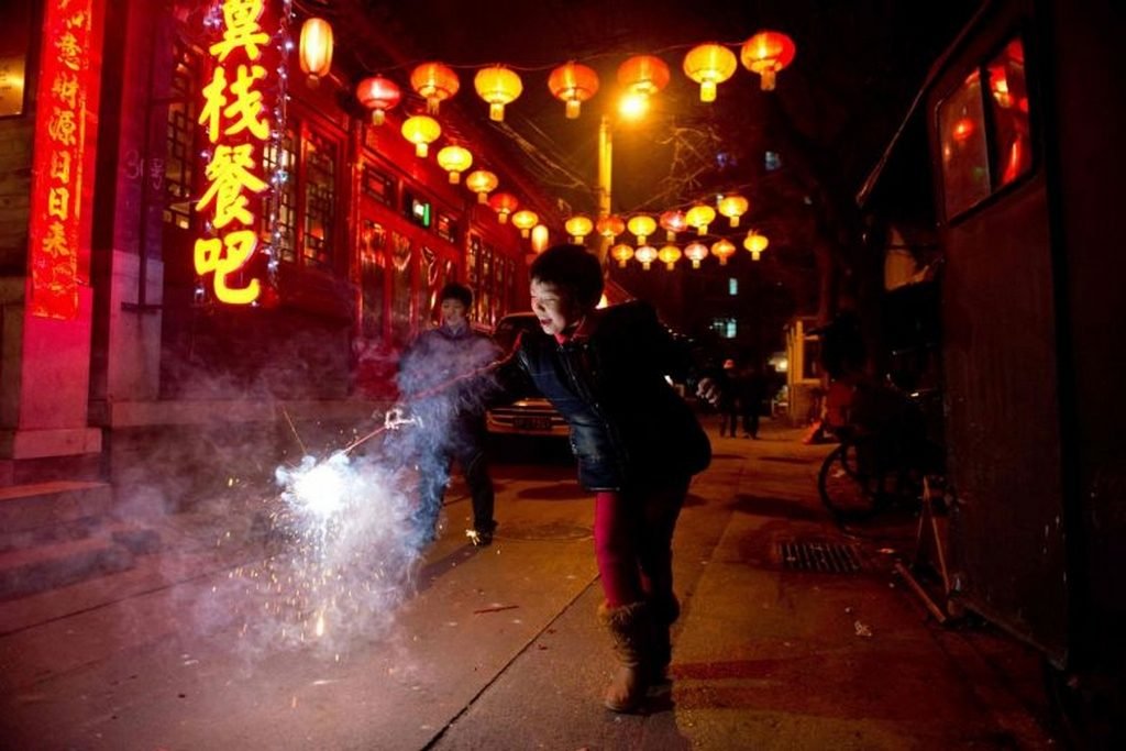 Photographie d'une jeune fille tenant un pétard dans une ruelle de Pékin lors de la fête des lanternes, le 24 février 2013.