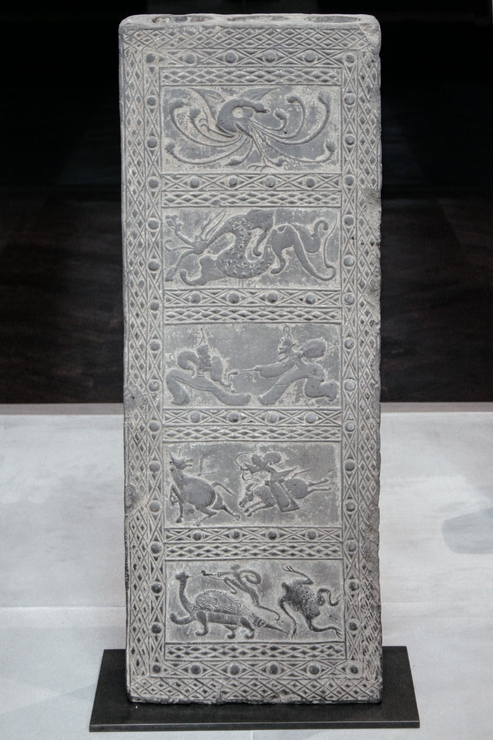 Stèle de terre cuite de la dynastie des Han, représentant des scènes de chasse et de bataille contenant des figures emblématiques des cinq directions cardinales, Musée Cernuschi,
